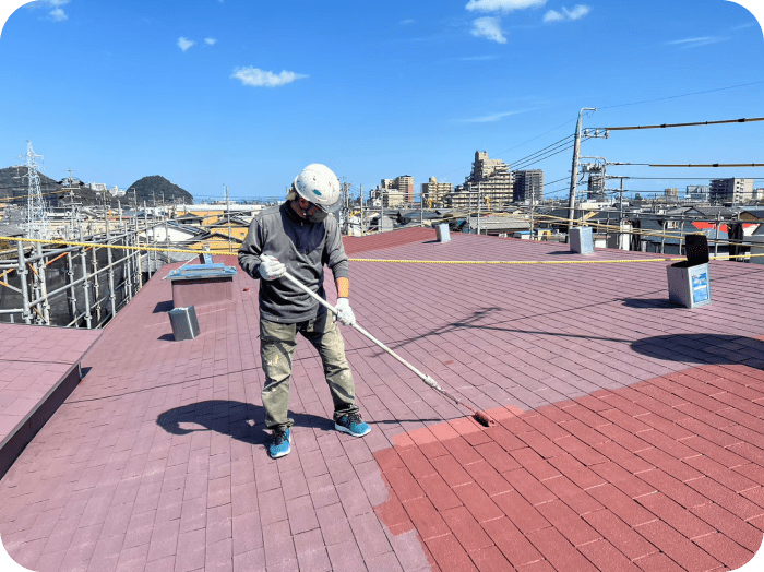 屋根を塗装している作業員